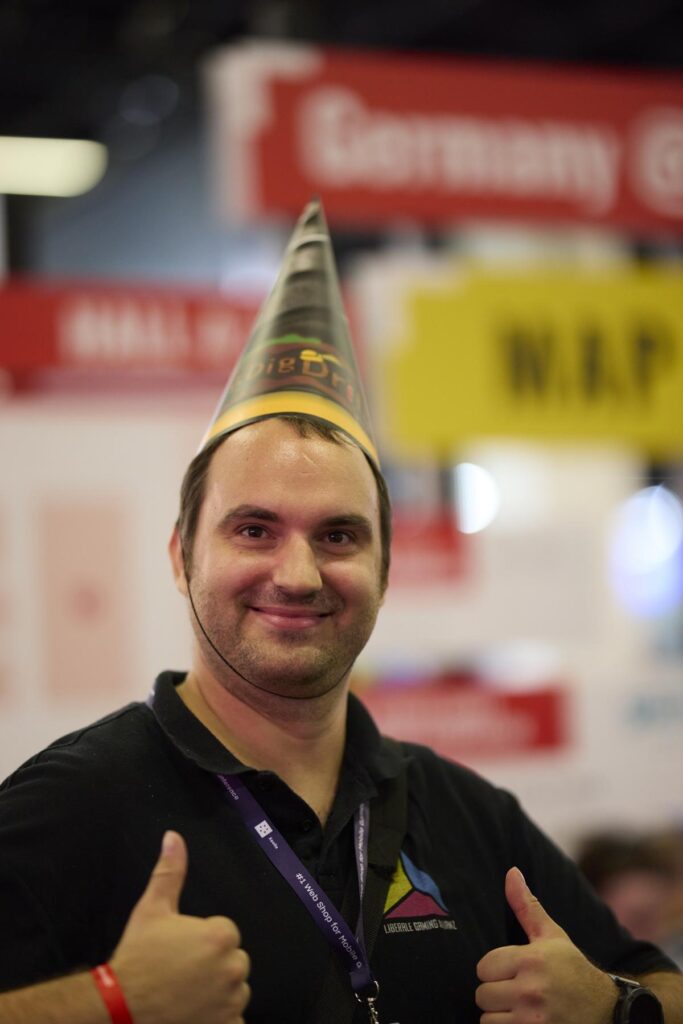 LGA-Mitglied mit Partyhut zeigt Daumen hoch auf der Gamescom 2025