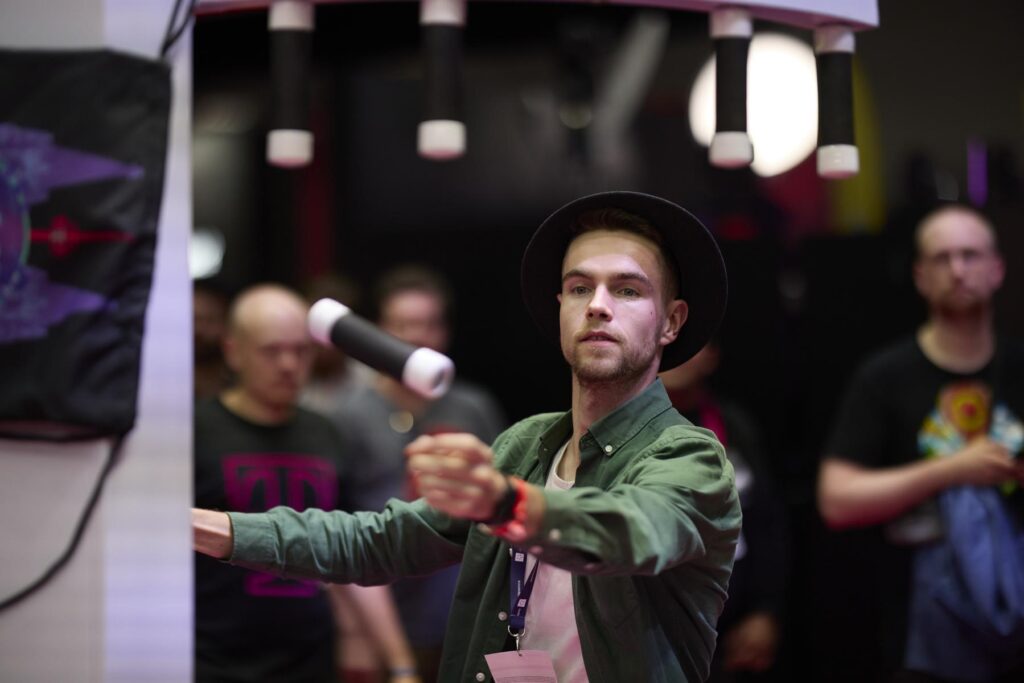LGA-Mitglied mit Hut spielt an einem Motion-Controller-Stand auf der Gamescom 2025