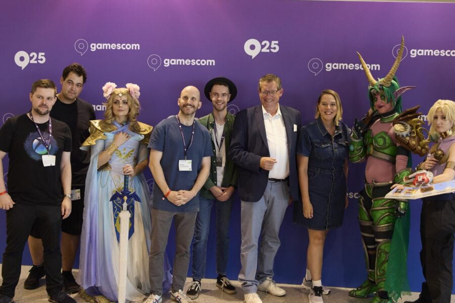 Gruppenfoto der LGA mit Dietmar Brockes (FDP, MdL NRW, im Sakko) und Cosplayern vor der Gamescom-Wand 2025
